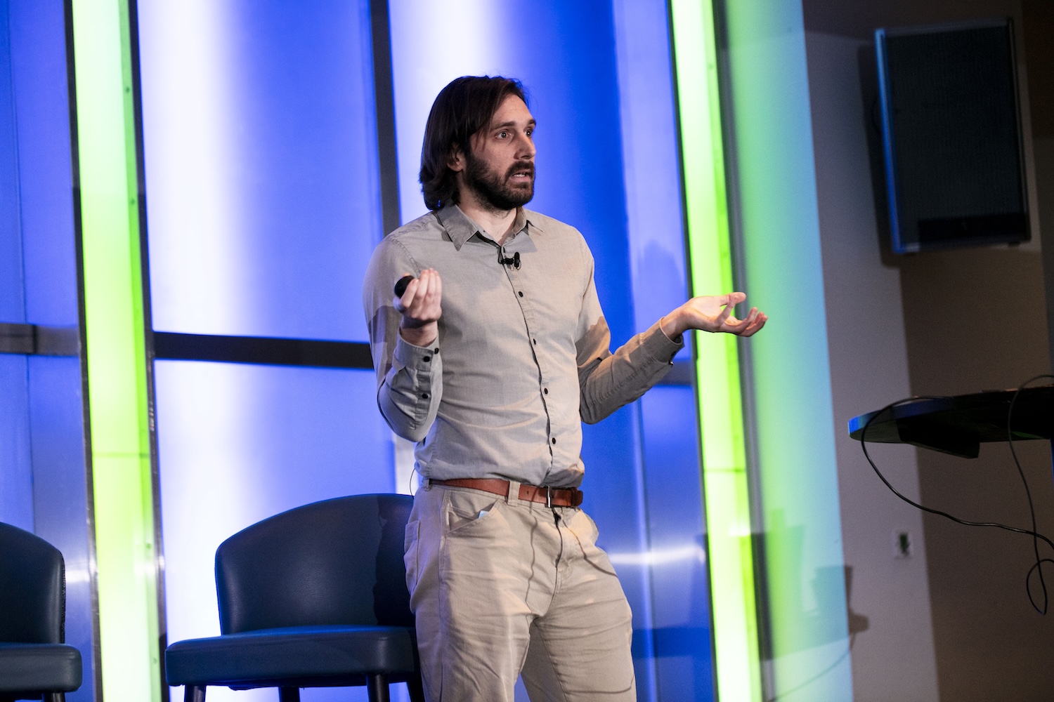 Colm Andrews gesturing with both hands as he presents on stage